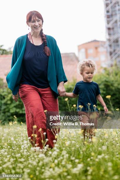 grandmother walking through tall grass with grandson - tall blonde women stock pictures, royalty-free photos & images