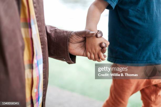 close up of grandfather holding grandson's hand - living coral stock pictures, royalty-free photos & images