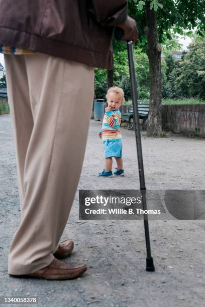 grandfather walking with cane and grandson - bastone foto e immagini stock