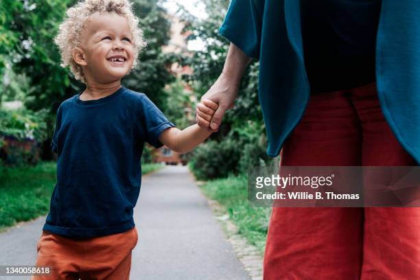 young boy smiling while holding grandmothers hand - begleiten stock-fotos und bilder