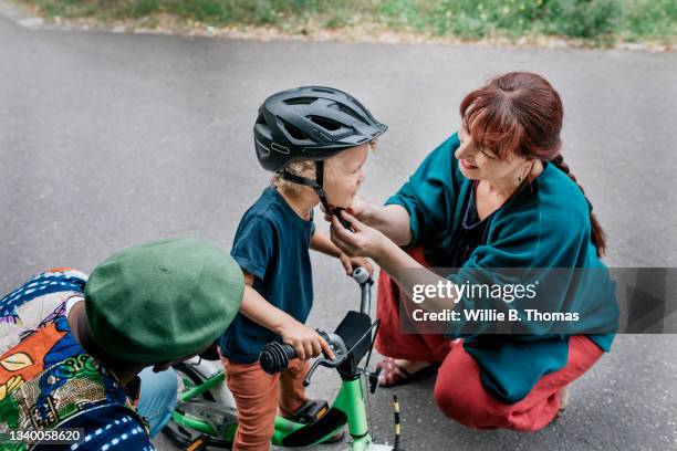 grandmother helping grandson fit helmet before bike ride - abbigliamento antinfortunistico foto e immagini stock