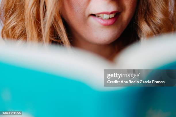 close-up of woman lips while she is reading a book - enzyklopädie stock-fotos und bilder