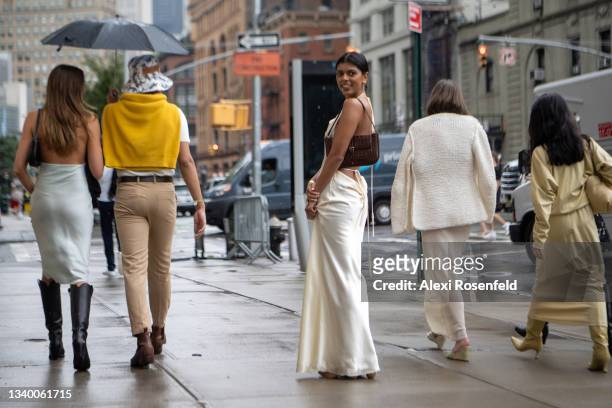 Woman wearing a white dress carrying a brown handbag looks back while walking outside Spring Studios on September 09, 2021 in New York City.