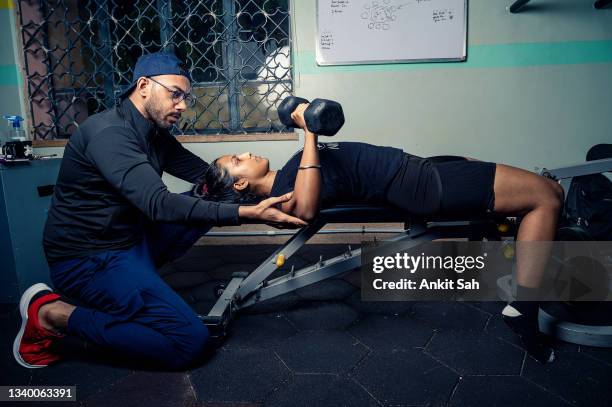 personal trainer helping young woman with her workout. - weightlifter stock pictures, royalty-free photos & images