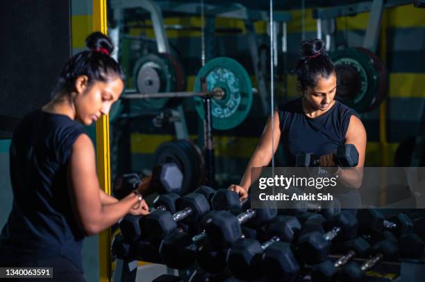young woman does dumbbell workout in a gym. - dumbbell stock pictures, royalty-free photos & images