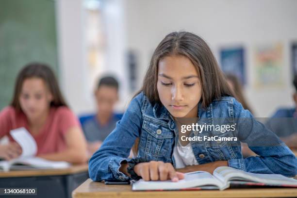 female student reading a book in a classroom - student reading stock pictures, royalty-free photos & images