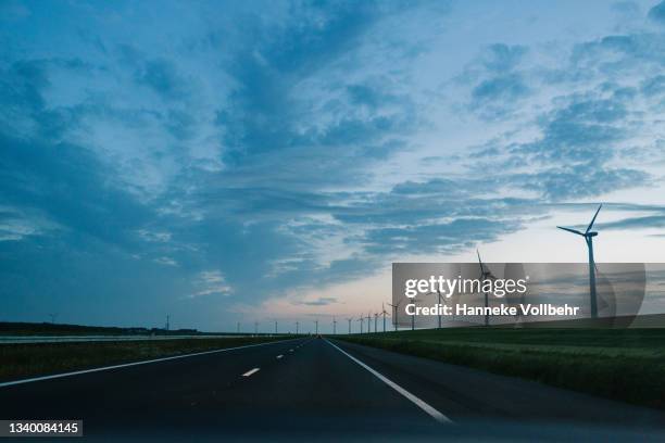 empty highway with wind turbines - windmill silhouette stock pictures, royalty-free photos & images