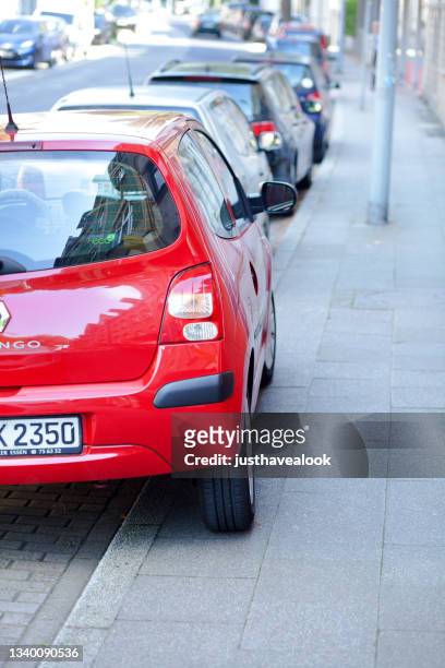 falsch geparktes rotes auto teilweise auf gehweg - sidewalk stock-fotos und bilder