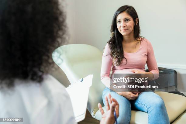 la futura madre toca el abdomen mientras escucha al médico irreconocible - embarazada fotografías e imágenes de stock