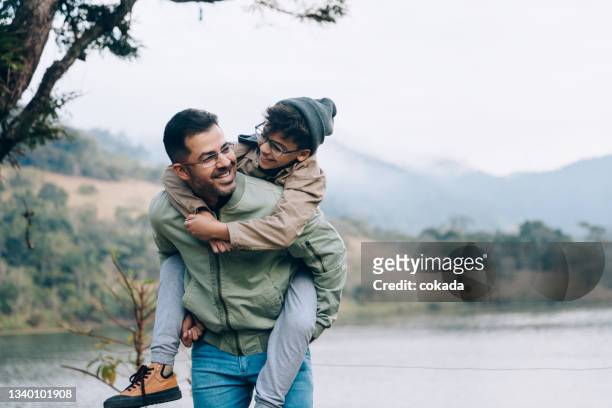 father carrying son on his back - papa stockfoto's en -beelden