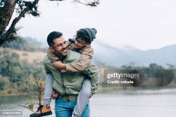 father carrying son on his back - father bildbanksfoton och bilder