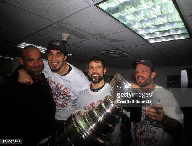 Scott Niedermayer of the New Jersey Devils celebrates in the locker room with the Stanley Cup Trophy with his teammates Scott Gomez, Ken Daneyko and...