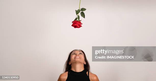 young smiling girl looking upwards at a rose on a white background - art modeling studio stock-fotos und bilder