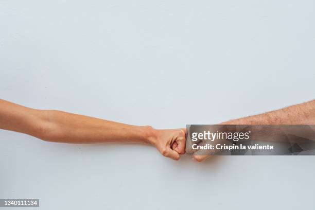 two people put fists together (or bump knuckles) to say hello on white background - hi five stockfoto's en -beelden