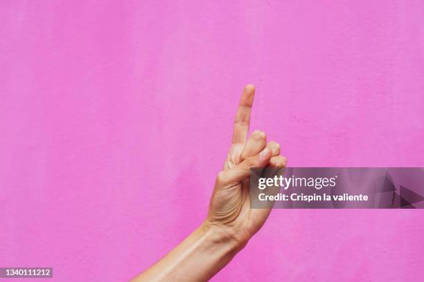 hand with one finger up isolated on pink background - doigt levé photos et images de collection