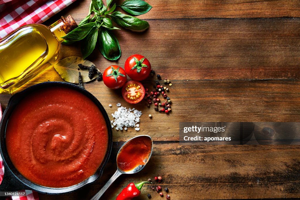 Tischansicht der Zutaten zur Zubereitung von Pasta und Tomatensauce in einer häuslichen rustikalen Küche mit Kopierraum