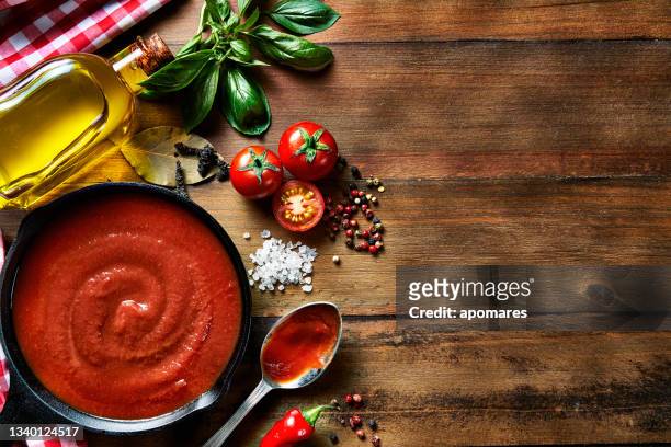 table top view of ingredients to prepare pasta and tomato sauce in a domestic rustic kitchen with copy space - sauce stock pictures, royalty-free photos & images