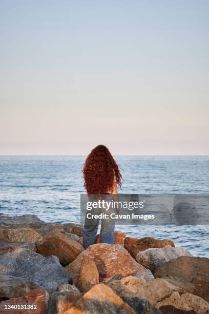 young redhead woman on her back looks to the sea - curly waves stock pictures, royalty-free photos & images