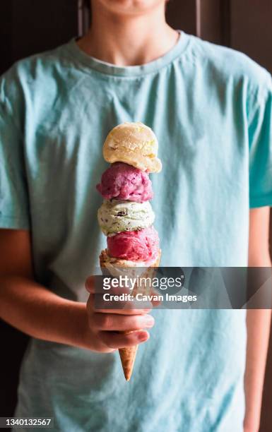 close up of child's hand holding large multi scoop ice cream cone. - ice cream cone stock pictures, royalty-free photos & images