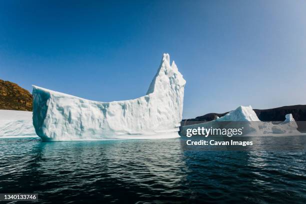 iceberg floating in ocean in the shape of a ship - baffinland stock-fotos und bilder