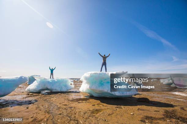 two men standing on sea ice chunks, iqaluit, canada. - iqaluit stock pictures, royalty-free photos & images