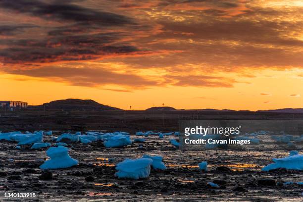 stunning sunset above shoreline littered with melting icebergs. - baffin island stockfoto's en -beelden