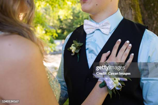 young woman wearing corsage touches her partners chest - corsage stock pictures, royalty-free photos & images
