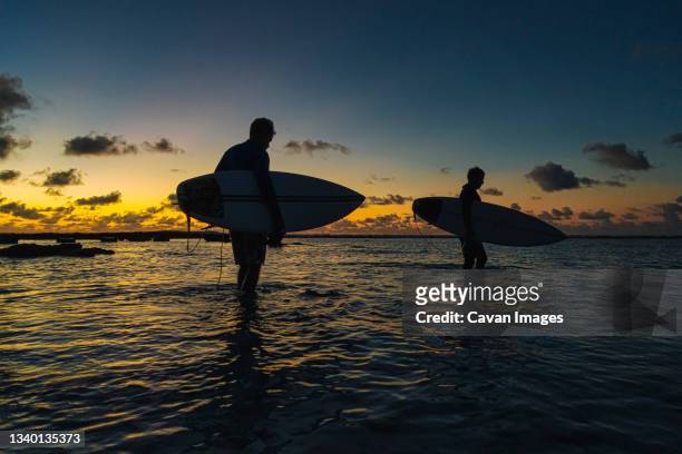 surfers at ocean coastline at sunset - beach morning glory stock pictures, royalty-free photos & images