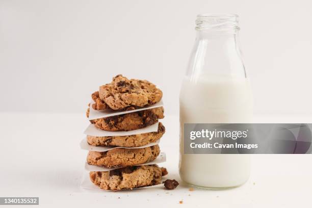 stack of chocolate chip cookies beside bottle of milk - milk and cookies stock pictures, royalty-free photos & images