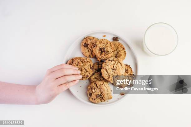 hand taking chocolate chip cookie from a plate - chocolate chip 個照片及圖片檔