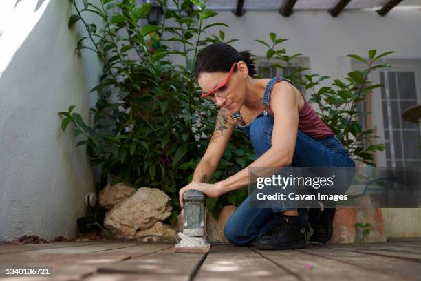 a young girl using an electric sander on wood flooring - thigh tattoo photos et images de collection