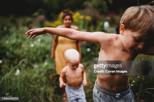 children walking among weeds with mom behind in a hot summer day - kids feet in home stock pictures, royalty-free photos & images