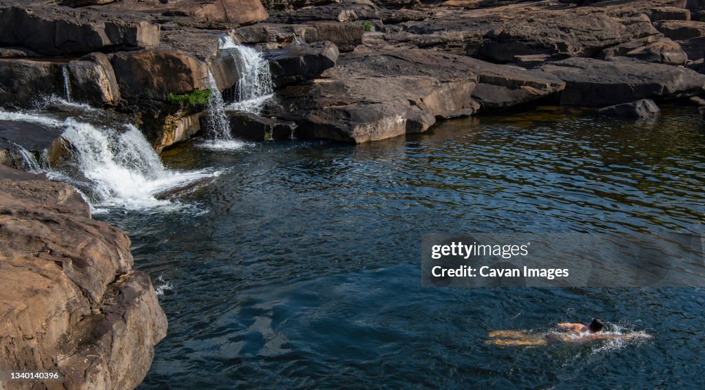 Man swimming below the Tatai waterfall in Cambodia