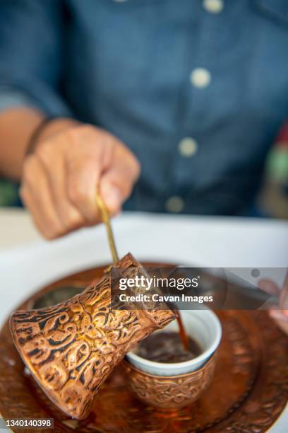 woman poring bosnian coffee into cup from dzezva pot - mostar stock-fotos und bilder