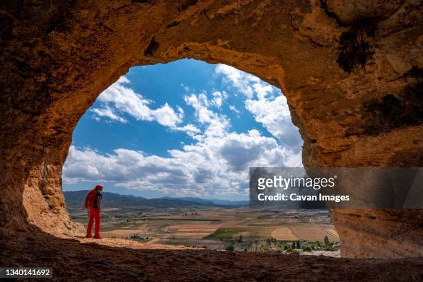 a women hiking a scenic trail under a giant overhang caves of zaen - murcia - fotografias e filmes do acervo