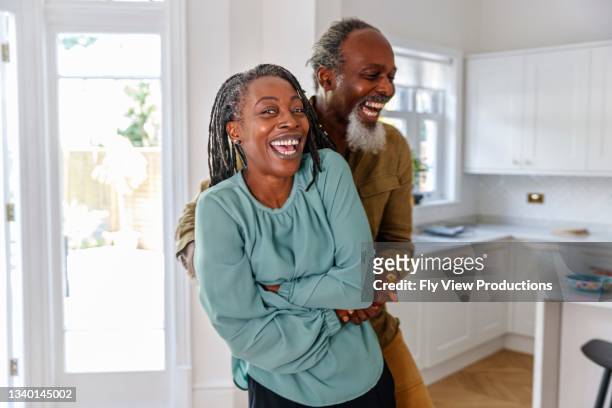 vibrant senior couple embrace and laugh while relaxing at home - couple dancing stock pictures, royalty-free photos & images