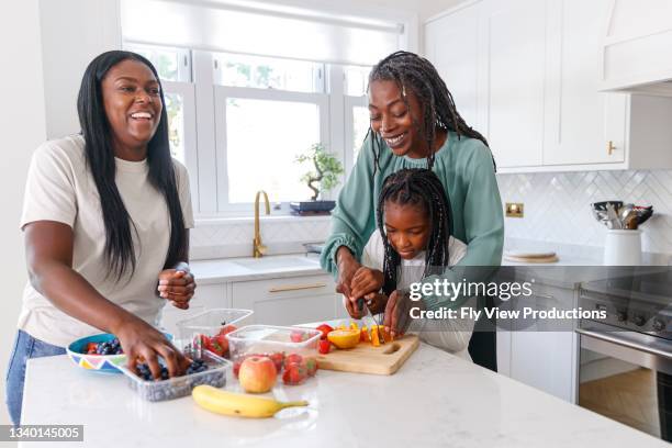 multi-generation family preparing healthy meal together - mother daughter cooking stock pictures, royalty-free photos & images