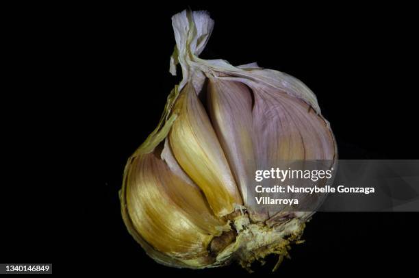 cloves of garlic on black background - garlic bulb half stock pictures, royalty-free photos & images