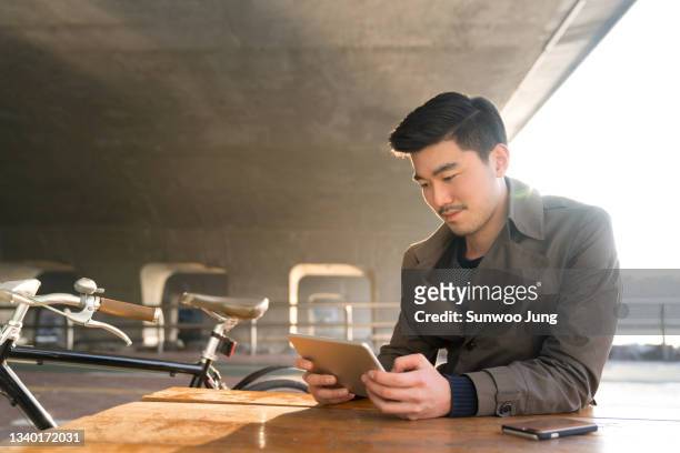 man on bicycle browsing tablet - korea technology stock pictures, royalty-free photos & images