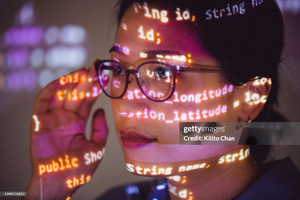Portrait of female programmer with program code projected on her face