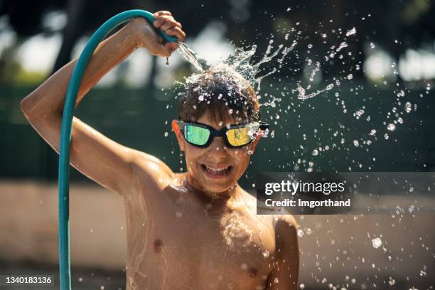 teenage boy cooling himself with a hose. - hyperthermia stock pictures, royalty-free photos & images