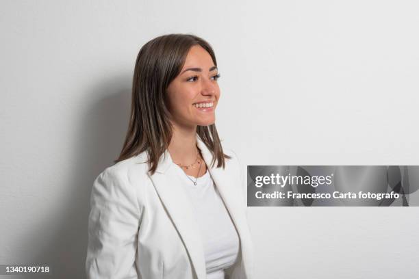 smiling young woman wearing white jacket - portrait white background looking away stockfoto's en -beelden