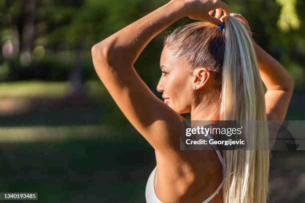 fittnes woman tying her hair - summer hair care stock pictures, royalty-free photos & images