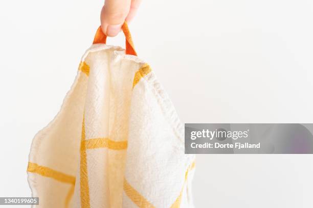 one clean white and yellow tea towel held between two fingers - straccio da cucina foto e immagini stock