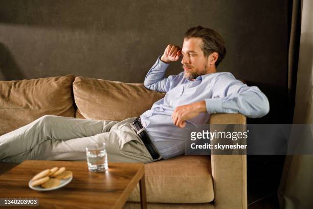 hombre de negocios pensativo relajándose en el sofá de casa. - psychiatrists couch fotografías e imágenes de stock