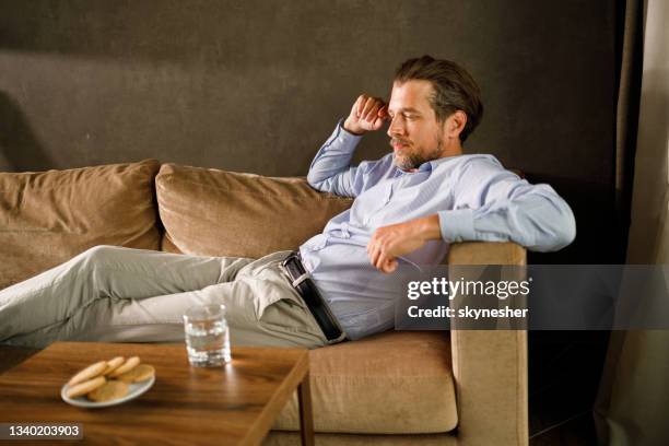 homem de negócios pensativo relaxando no sofá em casa. - divã de psiquiatra - fotografias e filmes do acervo