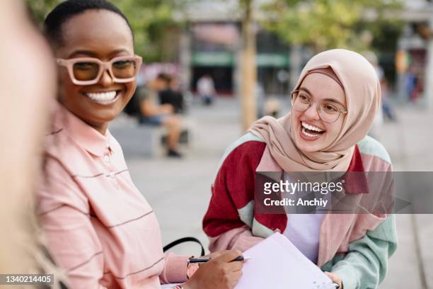 group of multiethnic students laughing and talking while studying outside - big fat white women stock pictures, royalty-free photos & images