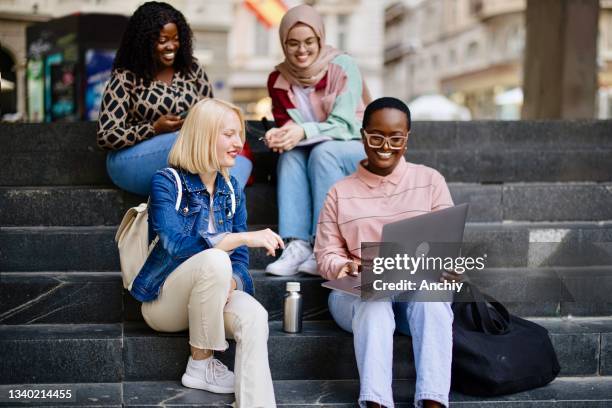 die schüler sitzen auf den stufen in der nähe des colleges und schauen auf den laptop und das digitale tablet und sprechen - big fat white women stock-fotos und bilder