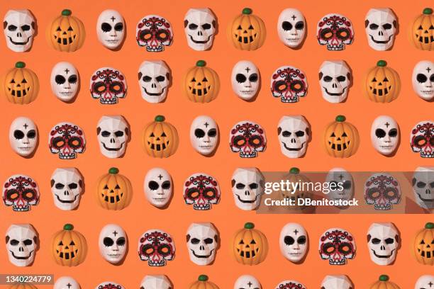 repeating pattern of skeleton masks, halloween killer with black circles and cross, pumpkin jack-o-lantern and mexican catrina on an orange background. halloween celebration concept. - catrina fotografías e imágenes de stock