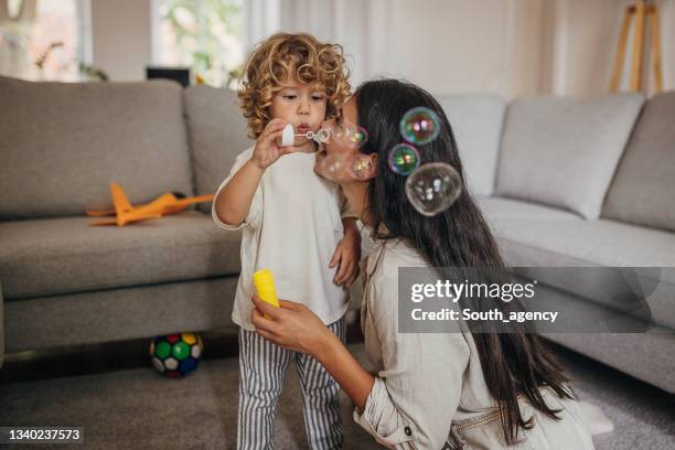 mamma e figlio che soffiano bolle a casa - bubble wand foto e immagini stock